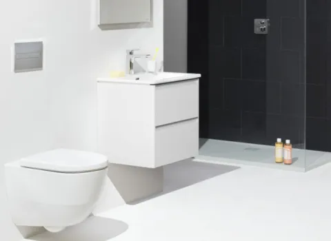 Ein modernes Badezimmer mit einem schwebenden weißen WC und einem schlichten Waschtisch mit zwei Schubladen.