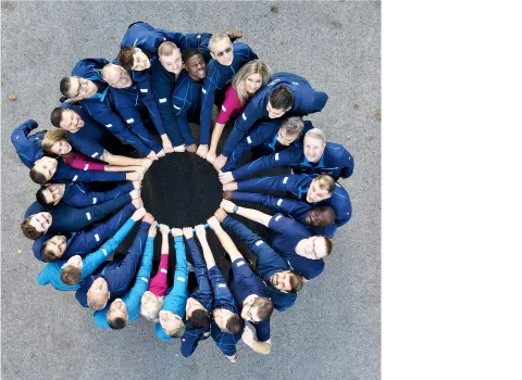 Das Team der Firma müller + sohn steht im Kreis und hält gemeinsam eine Ring. Symbolisch für Teamzusammenhalt.