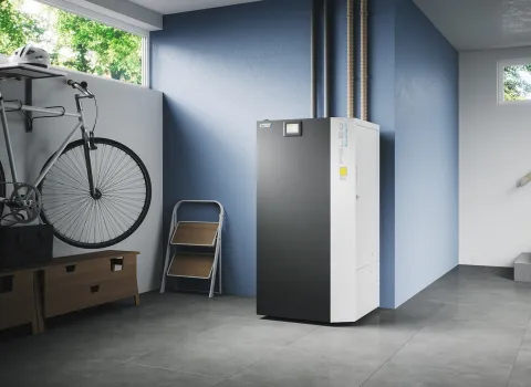 Die PELEO BlueTech Pelletheizung steht prominent in einem modernen Hauswirtschaftsraum mit grauen Bodenfliesen und blauen Wänden.