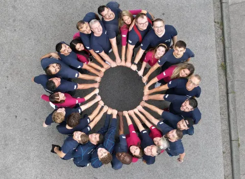 Das Team der Firma müller + sohn steht im Kreis und schaut nach oben in die Kamera.