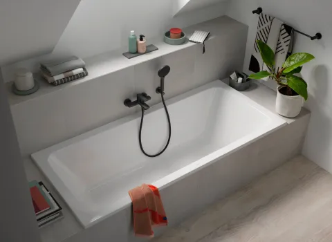 Rechteckige Badewanne aus der Kollektion D-Code von Duravit in modernem Dachgeschossbad mit grauen Fliesen und schwarzer Armatur.
