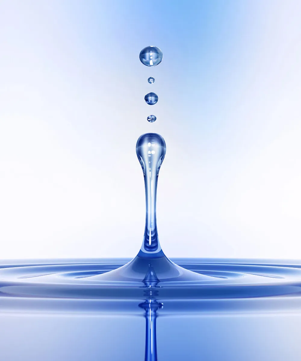 Ein Wassertropfen steigt nach dem Auftreffen auf die Oberfläche empor, umgeben von kleineren Tropfen in der Luft.