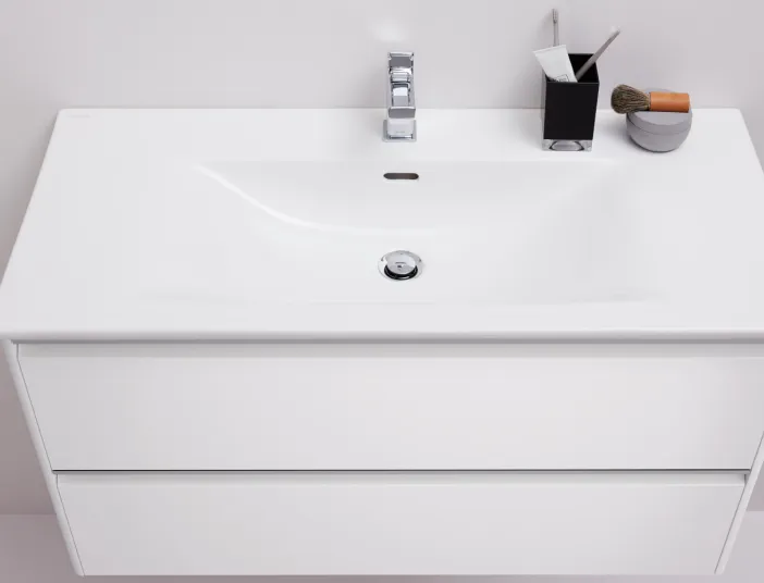 Eine weiße Waschbecken-Einheit mit klaren, minimalistischen Linien zeigt einen modernen Wasserhahn und eine breite Spüle.