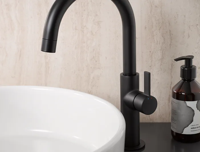 AquaXPro Slim Plus Waschtischarmatur in Schwarz matt neben einem weißen Aufsatzwaschbecken im modernen Badezimmer.
